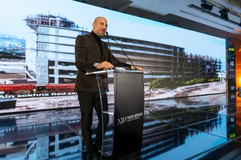 Girgis Youssef presenting beside a screen of project renderings